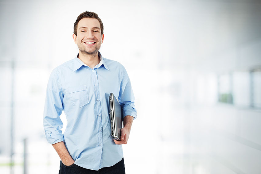 Você só pode colocar o anúncio de "vende-se empresa" quando tiver liberdade. A imagem mostra um homem feliz segurando o notebook no ambiente de trabalho.